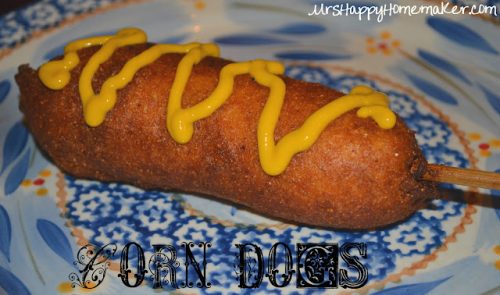 Homemade corn dog with mustard squiggled on top, sitting on a blue patterned plate