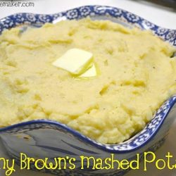 Mashed potatoes in a blue ruffled bowl with a pat of melting butter in the center