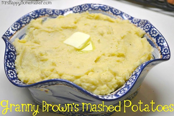 Mashed potatoes in a blue ruffled bowl with a pat of melting butter in the center