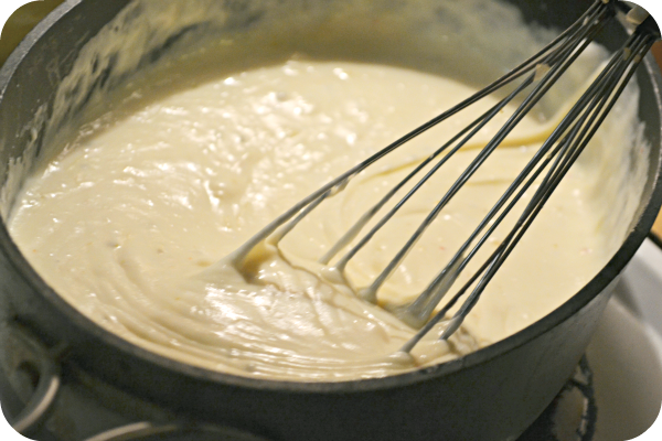 homemade cheese sauce being whisked in a small pot 