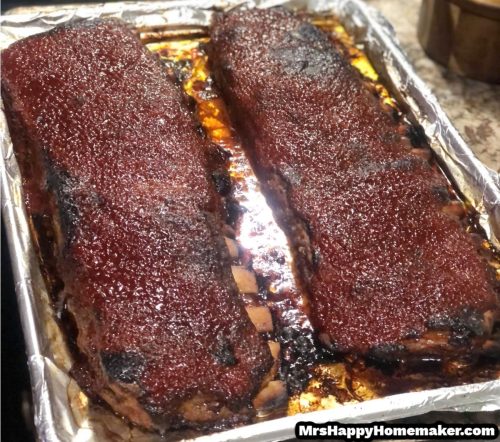 Two racks of baby back ribs on a baking sheet