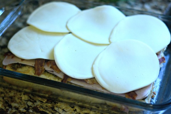 turkey bacon ranch sliders being prepared in a baking pan, topped with cheese
