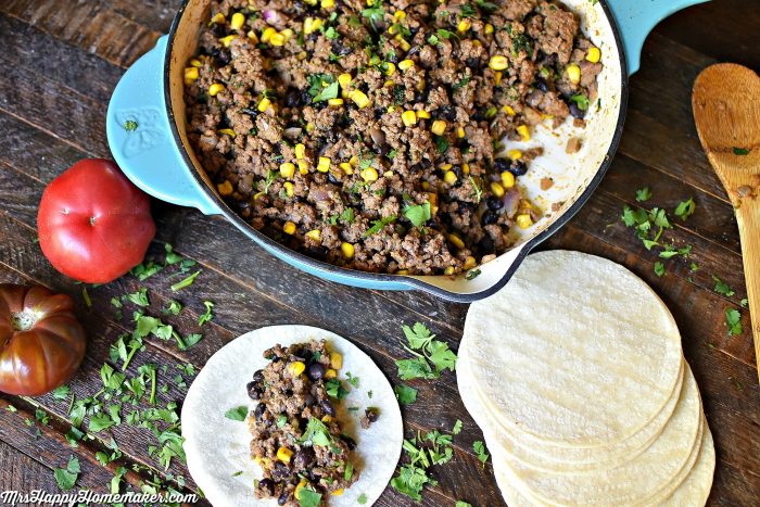 Taco filling in a skillet and flour tortillas