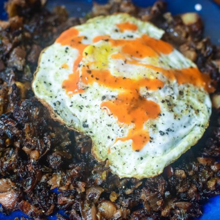 Brussel Sprout Breakfast Hash with a fried egg and drizzle of hot sauce