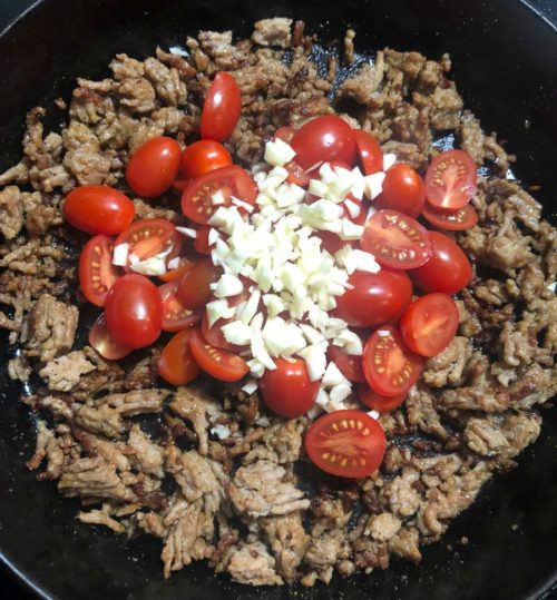 Meat and tomatoes in a skillet with garlic