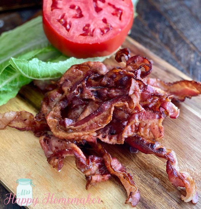 Air fryer bacon next to lettuce and a tomato 