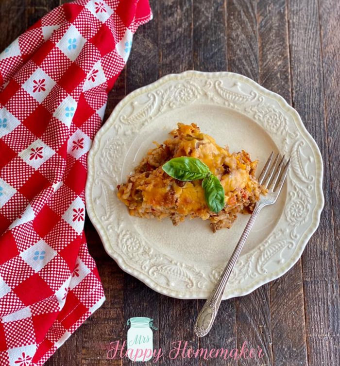 Stuffed bell pepper casserole on a white plate with a fork on it and a red checkered cloth 