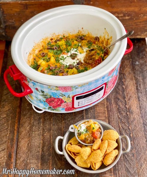 Crockpot taco dip in the crockpot with a bowl of Fritos corn chips