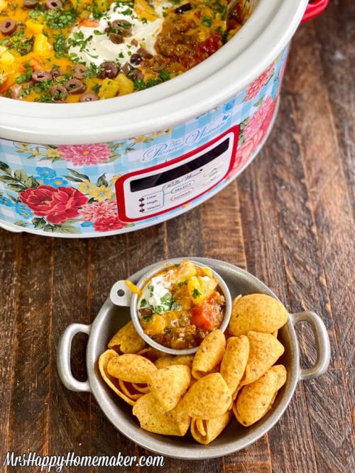 Crockpot taco dip with a bowl of Fritos scoops beside of it