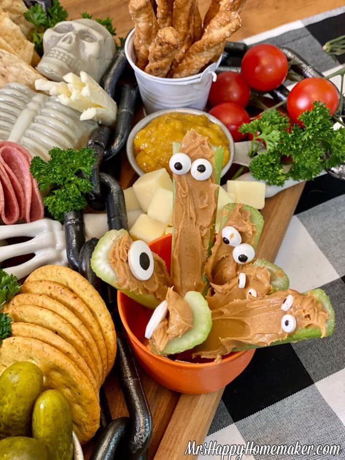 Peanut butter filled celery sticks with candy eyeballs on a charcuterie board 