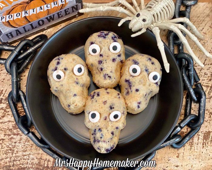 Skull shaped muffins with a plastic spider beside the black plate of muffins 