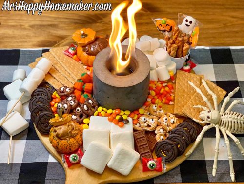 Halloween charcuterie board with a lit fire pit in the center of it.