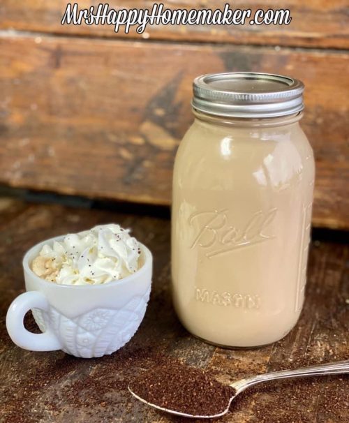 Make ahead lattes - one in a mason jar and one in a white cup topped with whipped cream. There is a spoon with coffee grounds in it beside of it