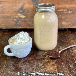 Make ahead lattes - one in a mason jar and one in a white cup topped with whipped cream. There is a spoon with coffee grounds in it beside of it