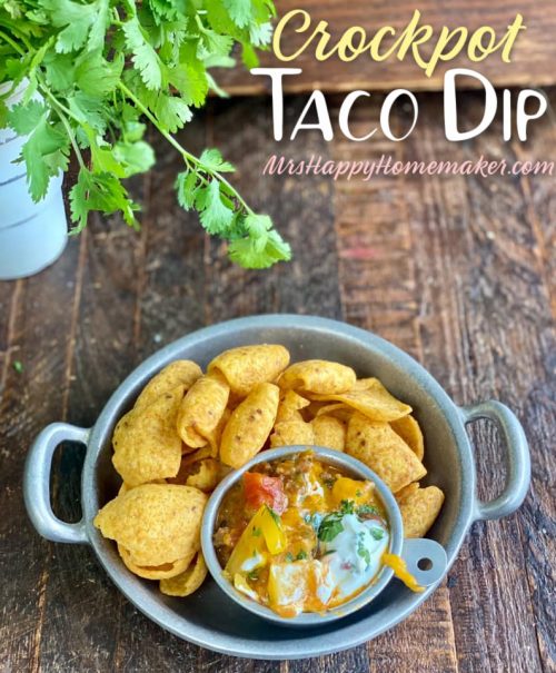 Crockpot taco dip in a small silver bowl surrounded by Fritos scoops