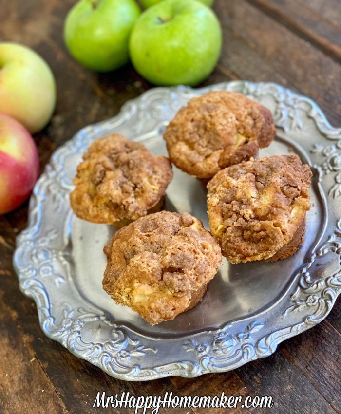 Apple pie muffins on a silver plate surrounded by apples