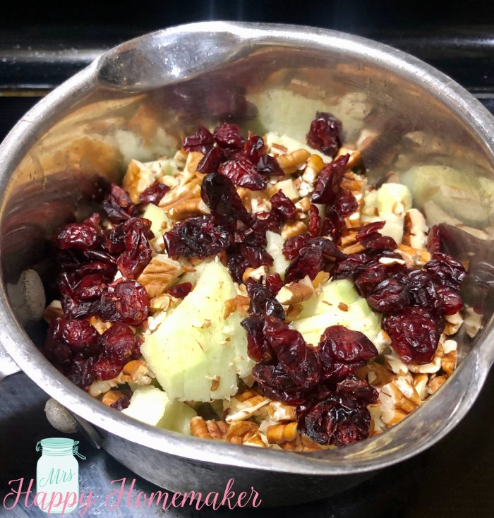 Apple and cranberries and pecans cooking in a saucepan