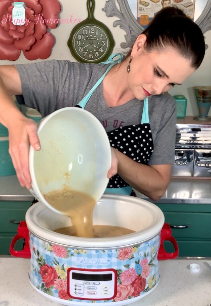 Mrs happy homemaker pouring gravy over the chicken in the crockpot