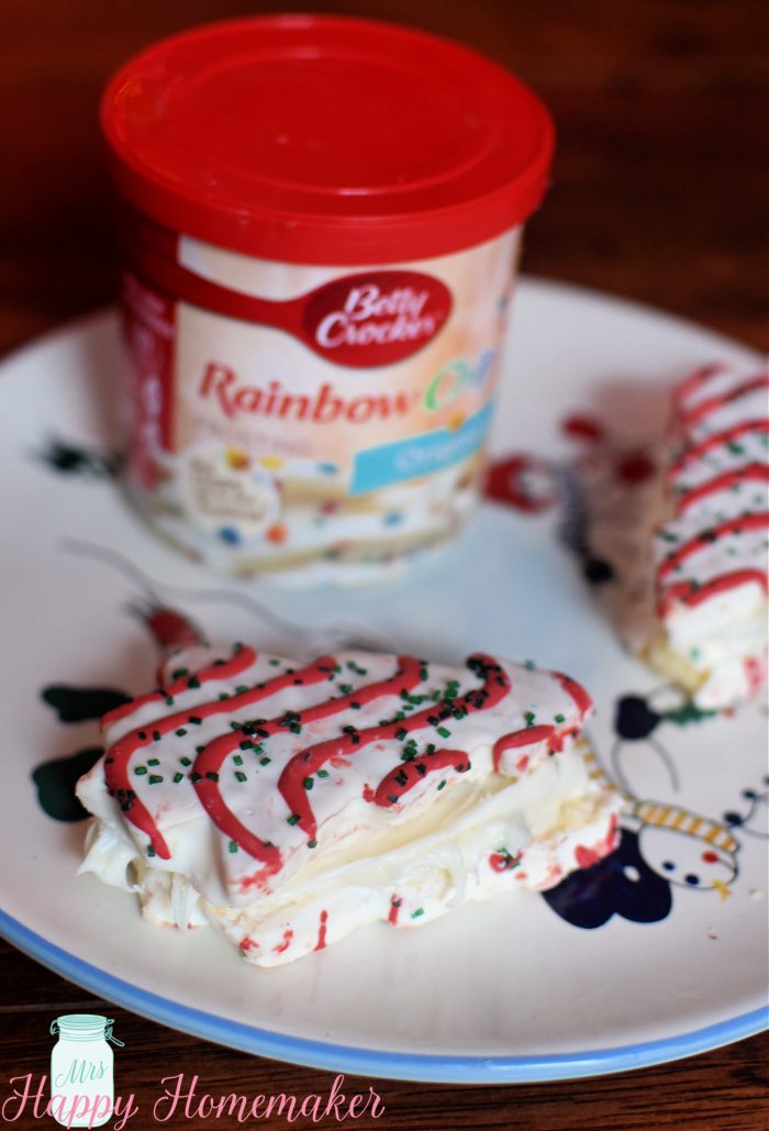 a container of frosting on a snowman plate with little debbie Christmas tree cakes 