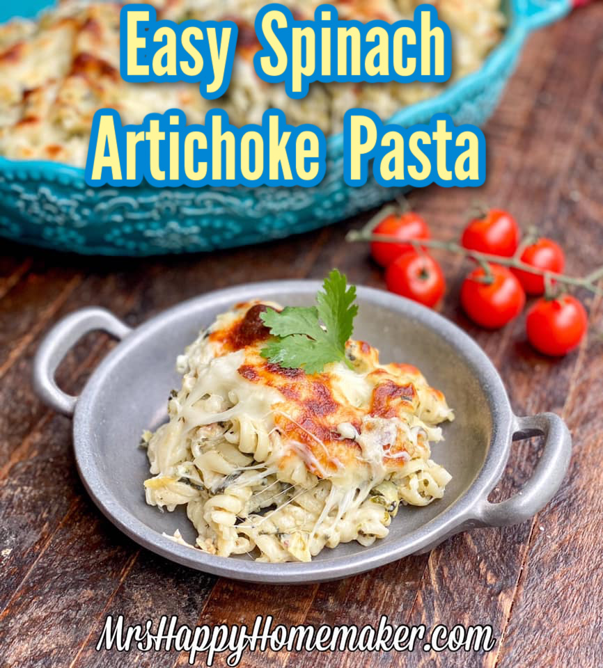Easy spinach artichoke pasta in a round silver dish with cherry tomatoes beside of it 