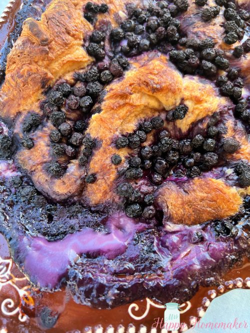 Blueberries and cream croissant French toast casserole in a brown rimmed casserole dish