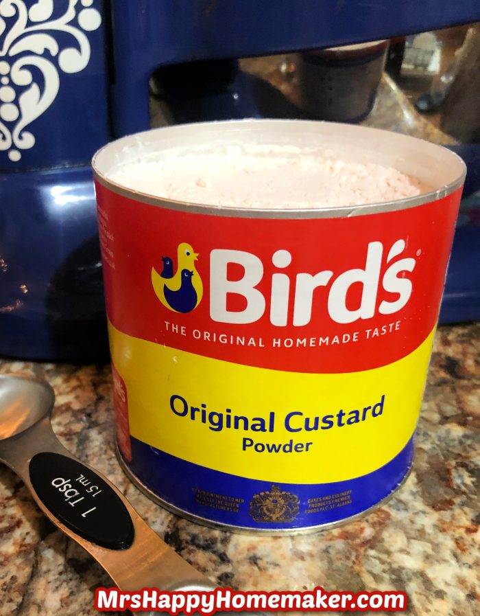 Birds custard powder, opened, on the counter with a tablespoon beside it