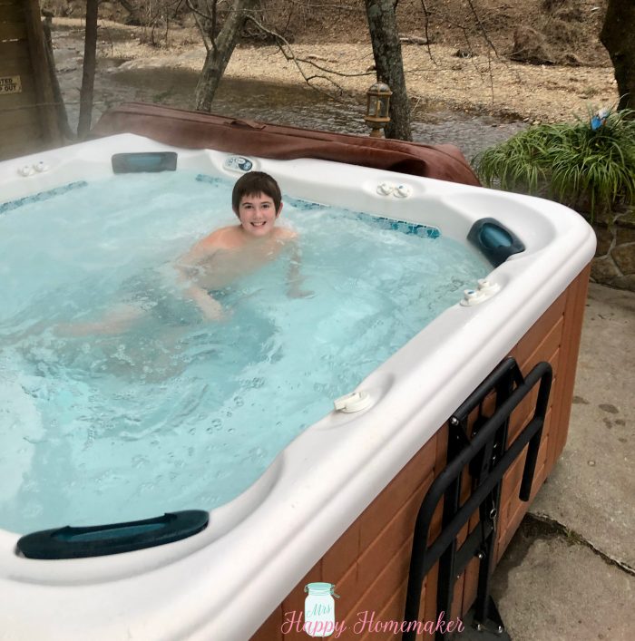 A hot tub with a young boy in it overlooking the river 