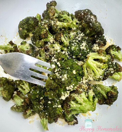 Air fryer broccoli in a white dish With a fork picking up the center piece