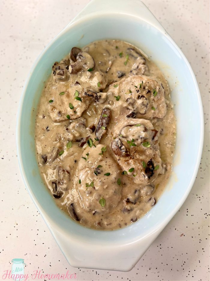 Mushroom gravy and pork chops in an oval white dish