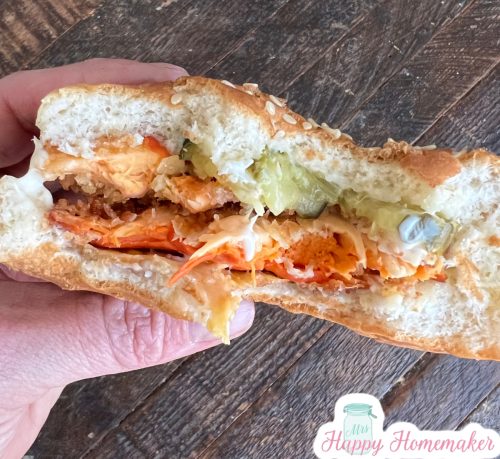 A half eaten vegetarian chick-fil-a chicken sandwich, being held in a hand
