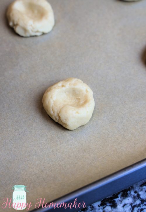 Thumbprint cookie dough on a baking sheet