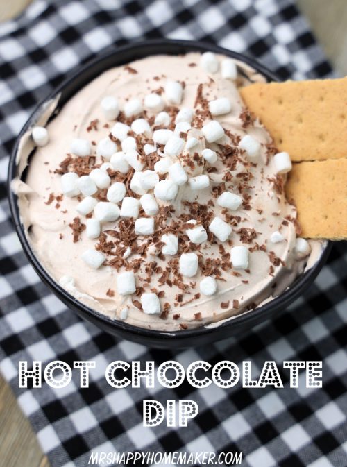 Hot chocolate dip with mini marshmallows and graham crackers on top on a Buffalo plaid cloth