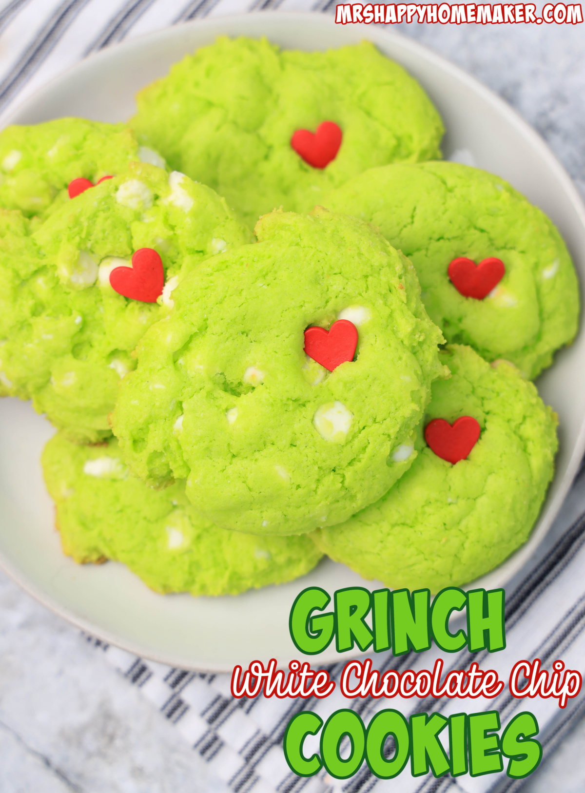 A white plate filled with green grinch cookies with a red heart in them