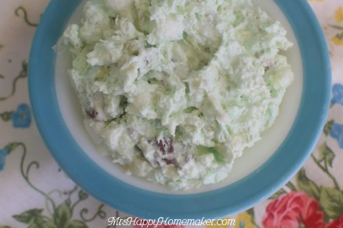 Watergate salad in a blue rimmed bowl on a floral tablecloth