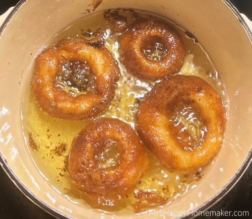 Onion rings frying in oil in a Dutch oven