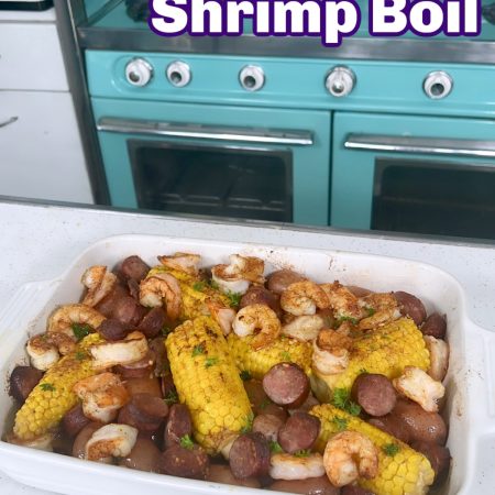 Sheet Pan shrimp boil in a white casserole dish with a vintage blue stove behind it