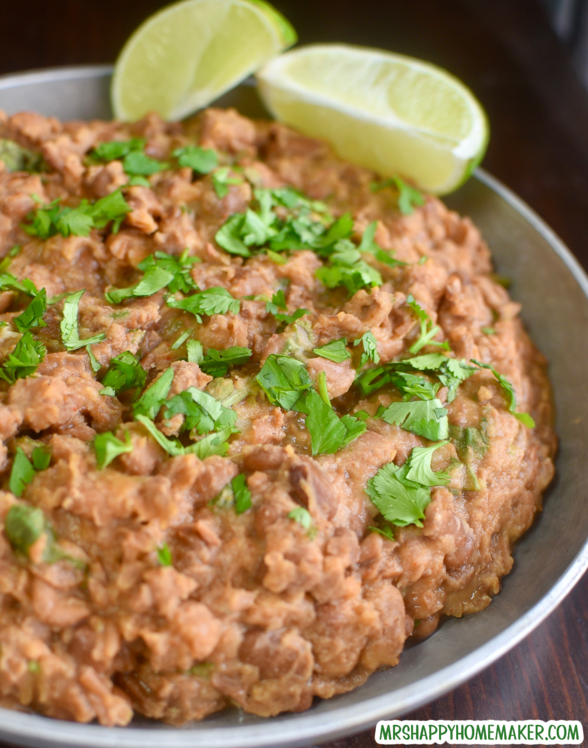 Easy homemade refried beans in a round silver bowl with 2 lime slices