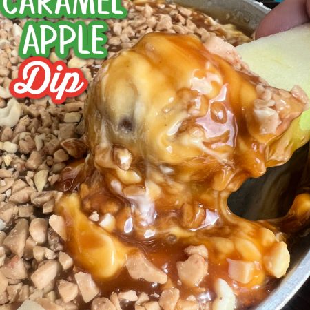 An apple being dipped into caramel apple dip in a silver dish