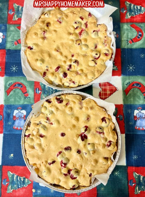 Cranberry Christmas Cake in two round aluminum pans that are lined with parchment paper, set on a holiday tablecloth