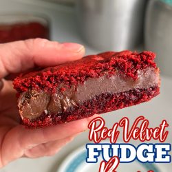 Red Velvet Fudge Bars being held in a hand over a blue rimmed white plate
