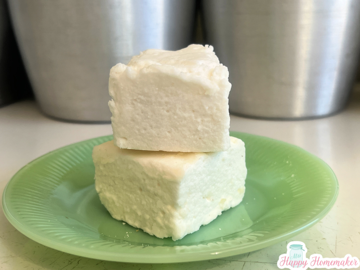 Two homemade marshmallows stacked on top of each other on a green jadeite plate