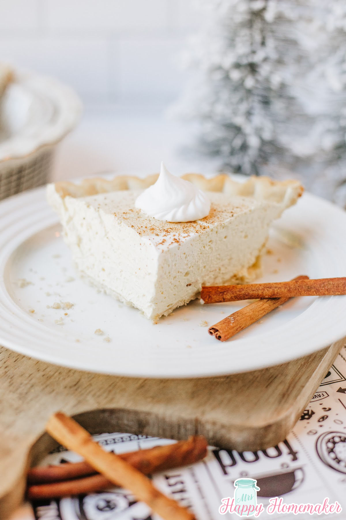 eggnog pie slice on a white plate with cinnamon sticks beside it
