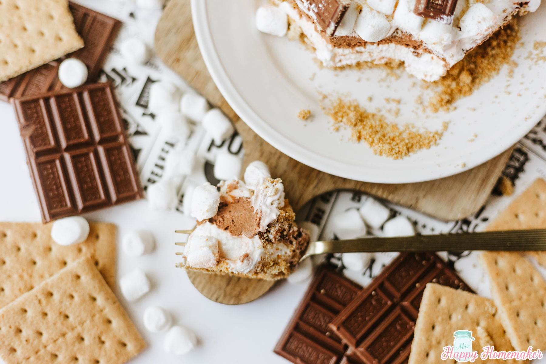 smores lasagna served on a white plate with a bite on a fork laying beside of it