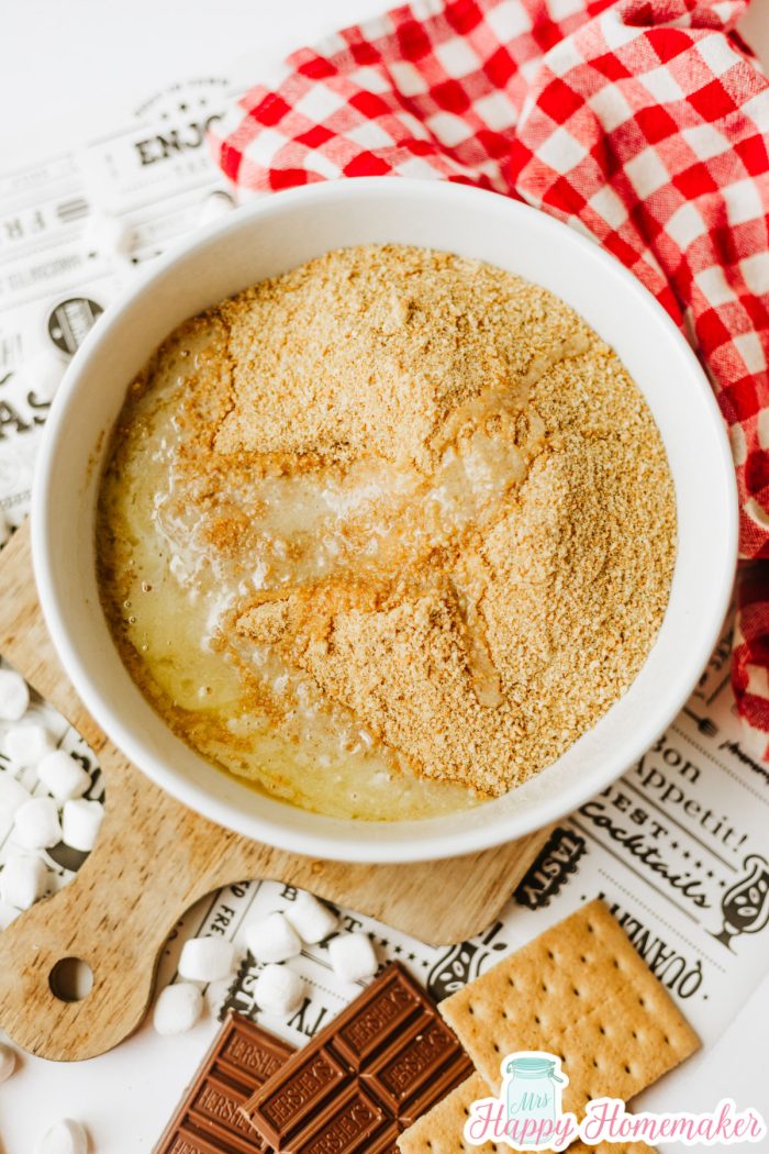graham cracker crumbs and melted butter mixed in a white bowl