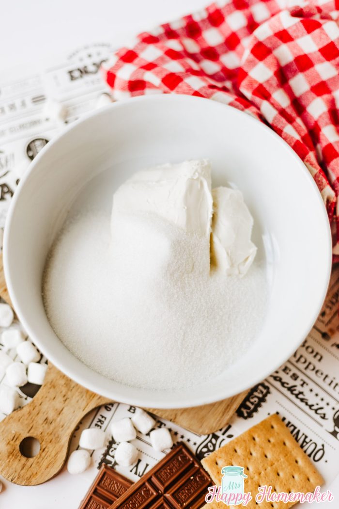 sugar and cream cheese being mixed in a white bowl