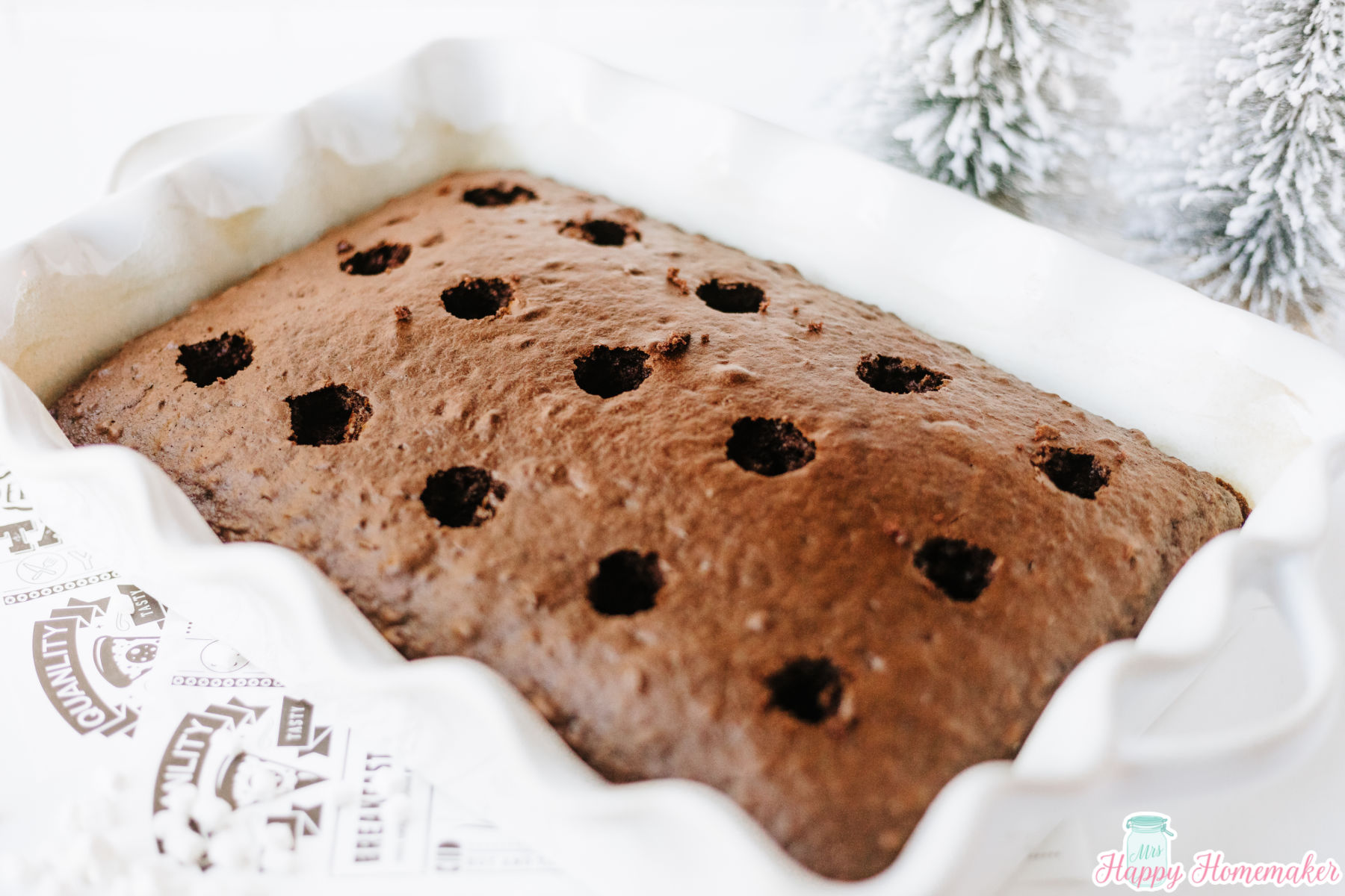 chocolate cake in a white cake pan with holes poked in the cake