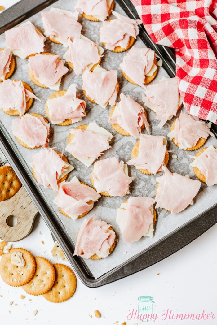 cheese and ham slices on a baking tray of ritz crackers