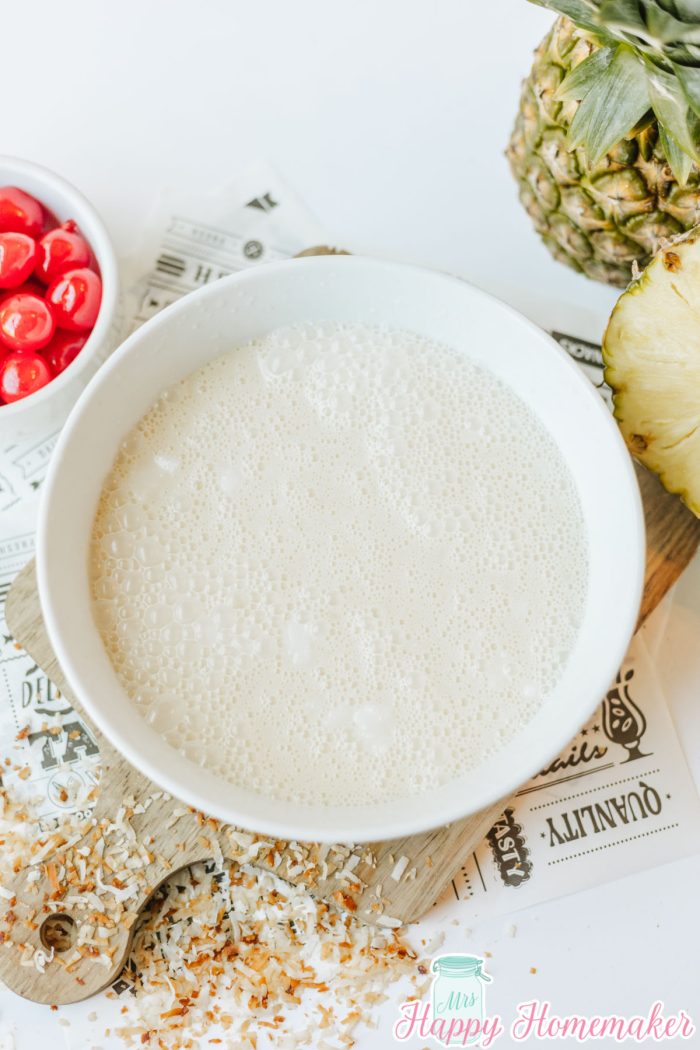 Simple & Easy Pina Colada Poke Cake filling mixed up in a white bowl