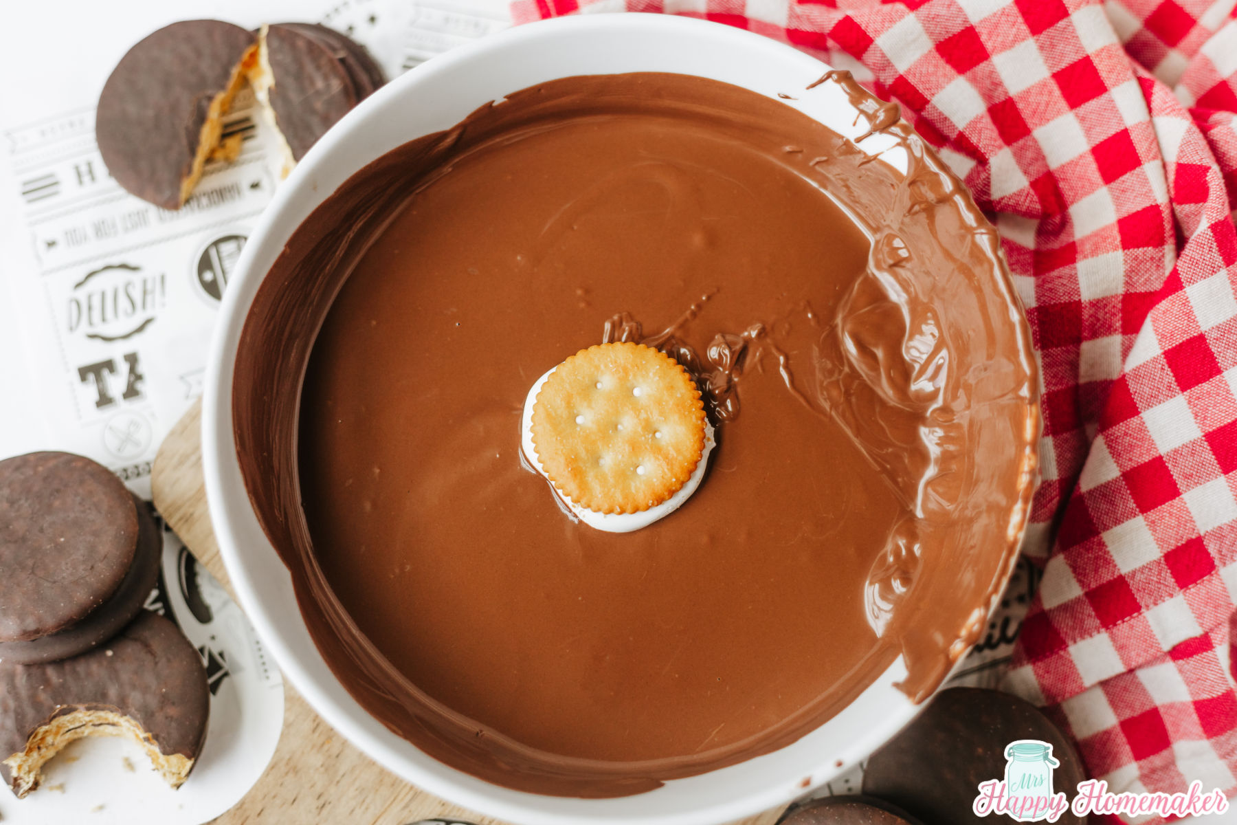 homemade moon pies being dipped in melted chocolate almond bark