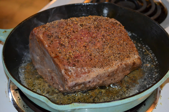 searing a round roast in a skillet